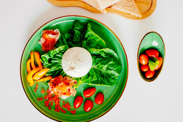 Burrata cheese served with tomatoes, yellow peppers, and red fish. Italian appetizer. The concept of a vegetarian lifestyle and healthy eating.