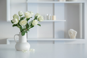 white roses in white jug in white interior