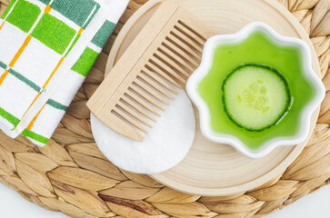 Wooden hairbrush, cucumber juice and cucumber slice for preparing homemade hair mask, face toner or eye mask. Natural beauty treatment and spa recipe.