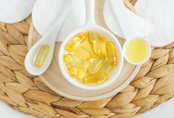 Small white bowl with cosmetic oil (face serum, cod liver oil, vitamin) capsules. Natural spa, skin...