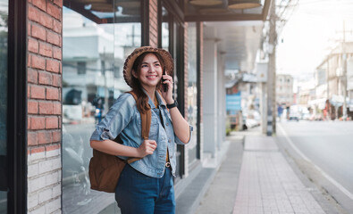 Young Asian tourist walking along city streets and holds a mobile phone on the payment