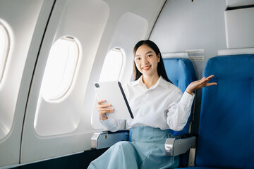 Asian executive excels in first class, multitasking with digital tablet, laptop. Travel in style,...
