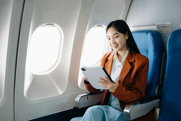 Asian executive excels in first class, multitasking with digital tablet, laptop. Travel in style,...
