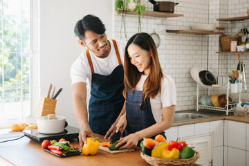 Happy asia young couple cooking together with vegetables with Bread and fruit in cozy on wooden kitchen table, love .