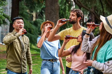 Five friends share laughter and drinks outdoors surrounded by greenery, embodying leisure and...