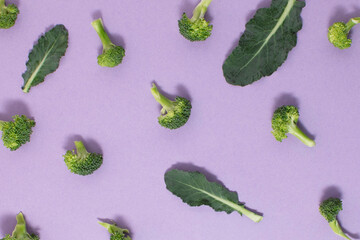 Pattern made of broccoli and leaves on a purple background. Creative food idea.