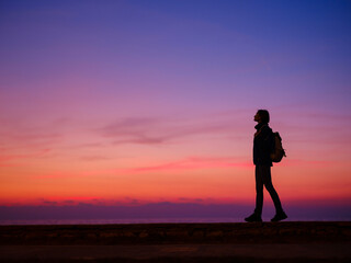 Woman tourist against sunset sky