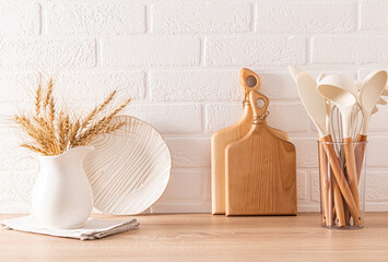Light kitchen background with wooden eco-friendly kitchen utensils and pitcher with ears of corn....