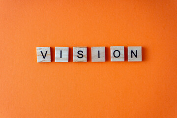 VISION wood word on compressed board with human's finger at N letter