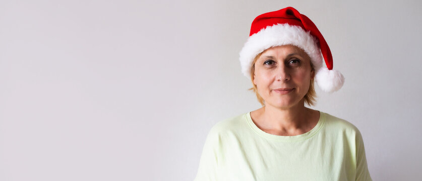 Close up photo of mature middle aged excited woman wearing christmas santa claus hat while celebrating new year party at home and having fun