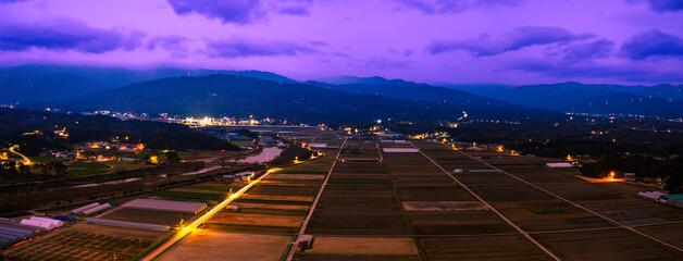 Fototapeta premium Odaesan Mountains National Park and Gangneung City agricultural field landscape in South Korea during winter rain and wind in November with snowy cloudscape at twilight