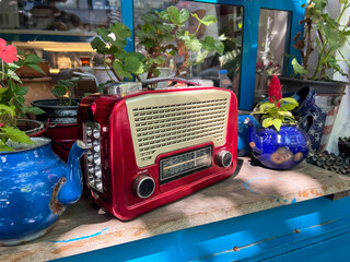 vintage radio tape and flowers in retro enamel tea pots on window sill