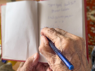 closeup wrinkled hand taking note on a notebook