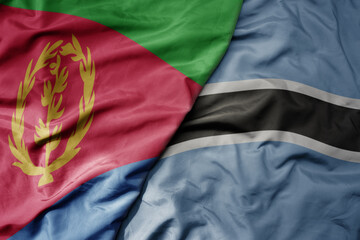 big waving national colorful flag of eritrea and national flag of botswana .