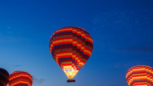 Fiery multicolored balloons soar into the sky with people in baskets.