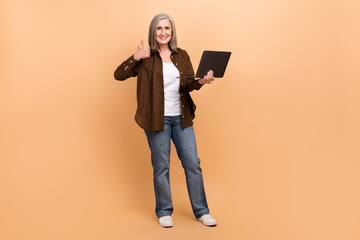 Full length photo of seo specialist woman thumb up confirm good job use laptop professional marketing job isolated on beige color background