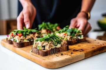 person spreading tuna salad on bread slices