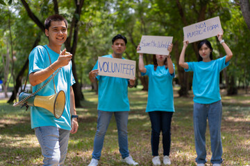 Obraz premium Happy young Asian students diverse volunteers hold a campaign sign for cleaning in the park, The concept of environmental conservation on world environment day, recycling, charity for sustainability.