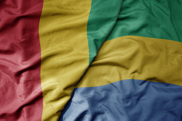 big waving national colorful flag of guinea and national flag of gabon .
