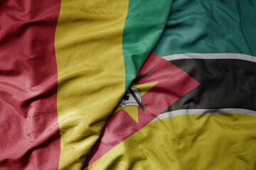 Fototapeta premium big waving national colorful flag of guinea and national flag of mozambique .