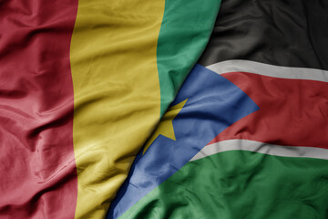 big waving national colorful flag of guinea and national flag of south sudan .