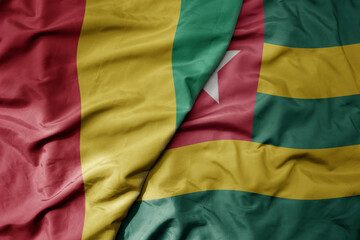big waving national colorful flag of guinea and national flag of togo .