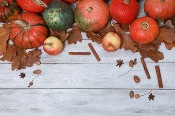 Orange pumpkinы, apples above copy space top view. Dry yellow oak leaves, acorns, spices on white wooden Thanksgiving table background. Autumn, fall menu, holiday, harvest season