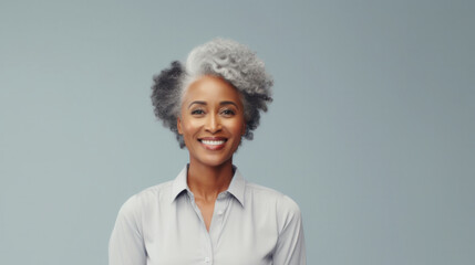 Radiant woman with striking gray hair and a warm smile, dressed in a crisp white shirt