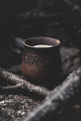 Candle in a brown clay pot on a wooden background