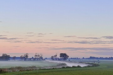 Pink morning sunrise sky with fog and mist across meadow and river