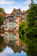 La Petite France is a picturesque “quartier“ in Strasbourg in Alsace, France. Idyllic view of colorful truss houses on the waterfront of old town channel system. Major tourist destination and sight. - obrazy, fototapety, plakaty