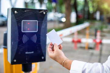Selective focus to RFID reader with blurry RFID card in hand of driver for automatic barrier gate system. Parking and automatic payment system with licence plate recognition. - obrazy, fototapety, plakaty