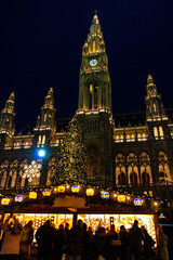 Obraz premium The illuminated shop at traditional Christmas market in front of Rathaus - City hall at Vienna, Austria.