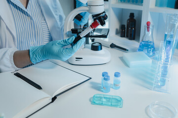 A chemist is using a microscope to search for chemicals from blood, Scientist is experimenting with chemicals in the laboratory, Chemist is separating compounds in test tubes with chemical reagents,