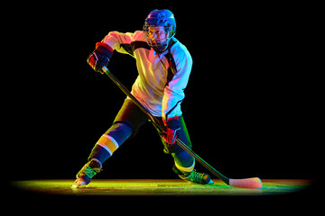Young woman, professional hockey player in motion, training, playing against black studio...