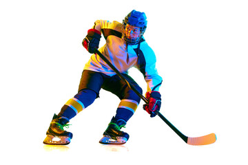 Young girl, hockey player in uniform and helmet training, standing with stick against white background in neon light. Concept of professional sport, competition, game, action, hobby, achievement