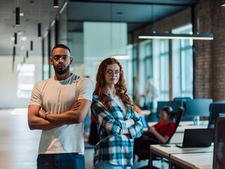 African-American businessman and his businesswoman colleague stand at the forefront with crossed arms, exuding confidence and leadership, while their diverse team diligently works behind them