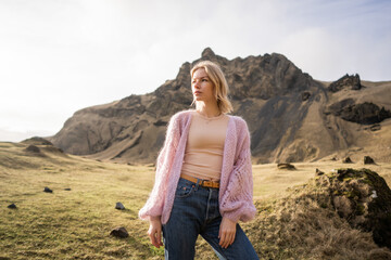 Naklejka premium Fashion girl in a purple jacket poses in mountains
