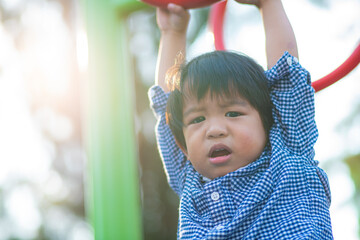 Little 2 - 3 year asian boy climbing on bar in outdoor playground city park