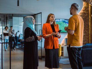 A group of young business colleagues, including a woman in a hijab, stands united in the modern...