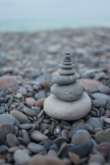 Fototapeta na wymiar pebble stones stacked in a pyramid in the sand near the seashore