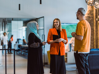 A group of young business colleagues, including a woman in a hijab, stands united in the modern...