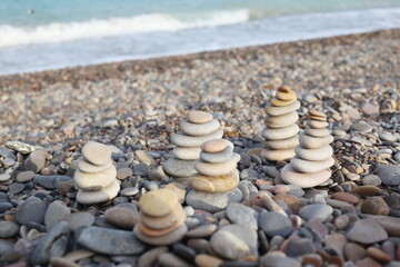 Fototapeta na wymiar pebble stones stacked in a pyramid in the sand near the seashore