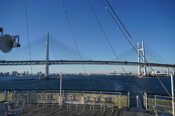 横浜、クルージング、横浜港、船上、橋、骨組み、鉄骨、甲板、椅子、風景、ベイブリッジ、橋、日本、神奈川、海、空、青、雲、屋外、冬、観光、サイトシーイング、旅、ツアー、景色、湾、ビル、建物、船、日本、船、客船、観光船、
