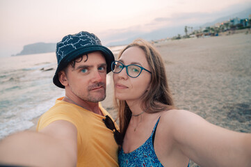 Happy couple taking a photo on a beach at the sea in Alanya city, Turkey. Travelling or vacation concept