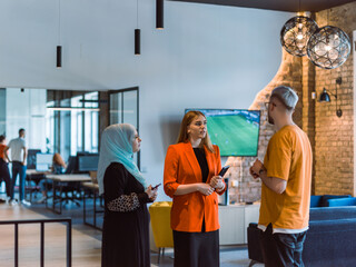 A group of young business colleagues, including a woman in a hijab, stands united in the modern corridor of a spacious startup coworking center, representing diversity and collaborative spirit