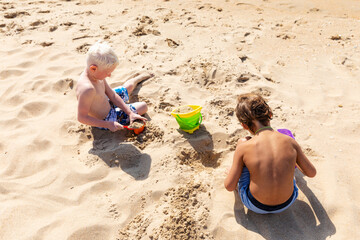 Children two little boys playing on the beach on summer holidays. Children having fun with a sand...