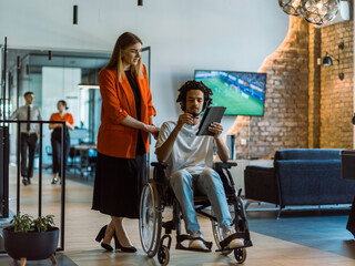 African-American businessman in a wheelchair engages in a collaborative discussion, using a tablet, with his business colleague, exemplifying the seamless integration of adaptive technology and