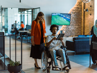 Fototapeta na wymiar African-American businessman in a wheelchair engages in a collaborative discussion, using a tablet, with his business colleague, exemplifying the seamless integration of adaptive technology and