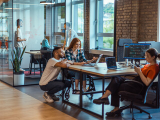 A diverse group of young business individuals congregates in a modern startup coworking center,...